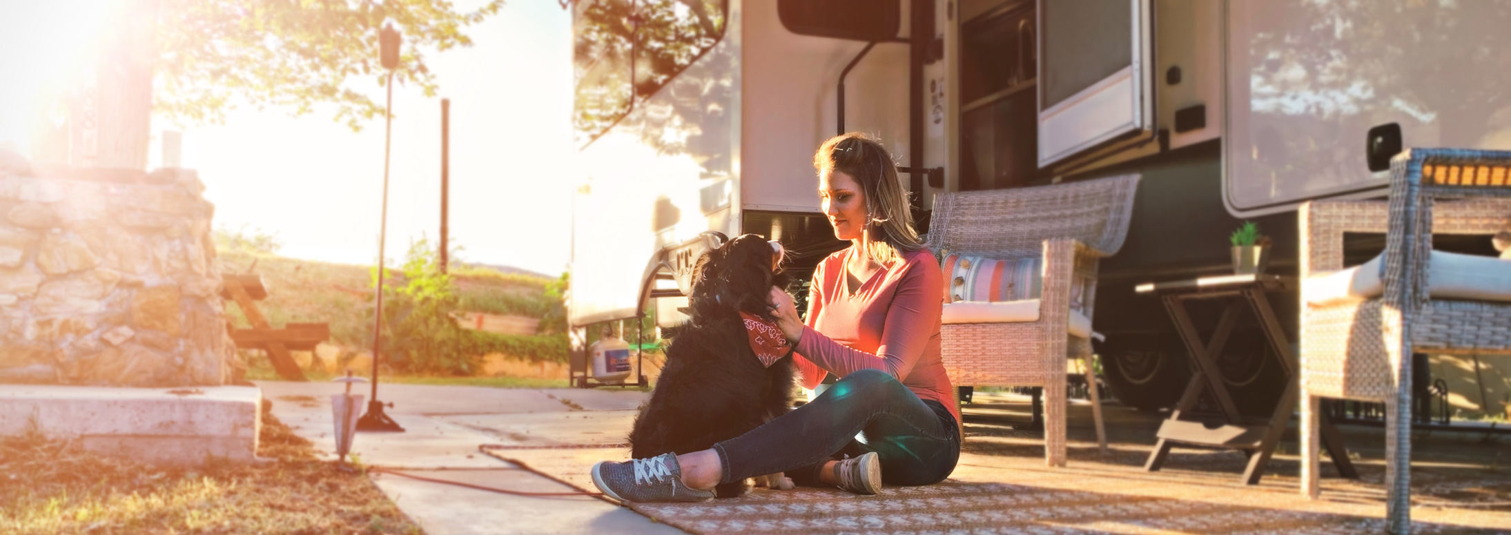 Woman sitting with dog in front of a Cedar Creek fifth wheel